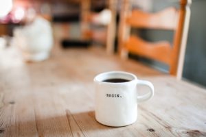 White ceramic mug with "begin" written on it.