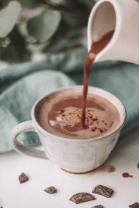 Hot chocolate pouring in a white mug.