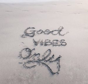 "good vibes only" written on a beach