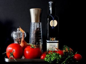 A bottle of extra-virgin olive oil and tomatoes