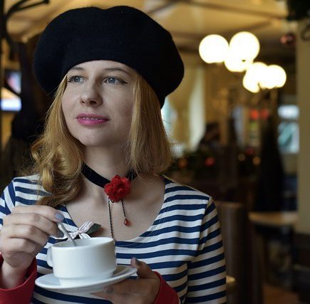 A French woman sipping a coffee at a cafe
