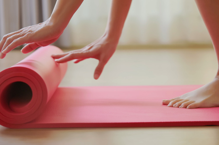 stay motivated to workout-woman rolling pink yoga mat