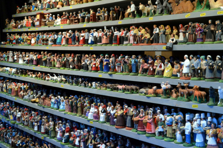 unusual regional french christmas traditions-several hundred santons of provence placed in a row on shelves