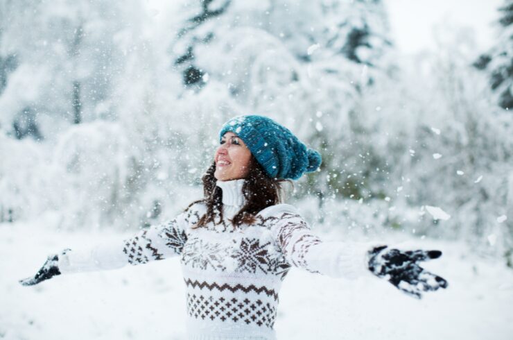 Christmas mental health tips-woman in winter forest playing with snow