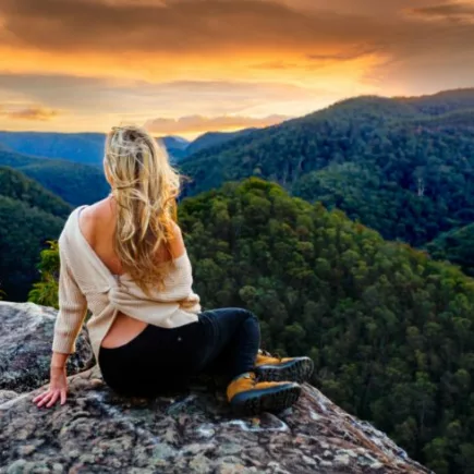 slow life tips-a woman on a peak watching sunrise and mountains