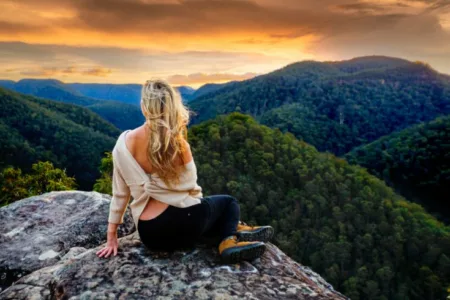 slow life tips-a woman on a peak watching sunrise and mountains