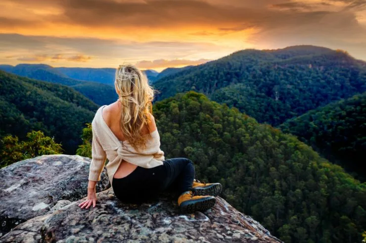slow life tips-a woman on a peak watching sunrise and mountains