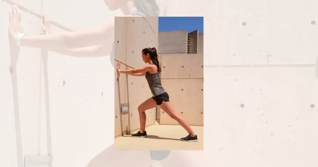 woman stretching calves standing against the wall-beginner ballet stretches
