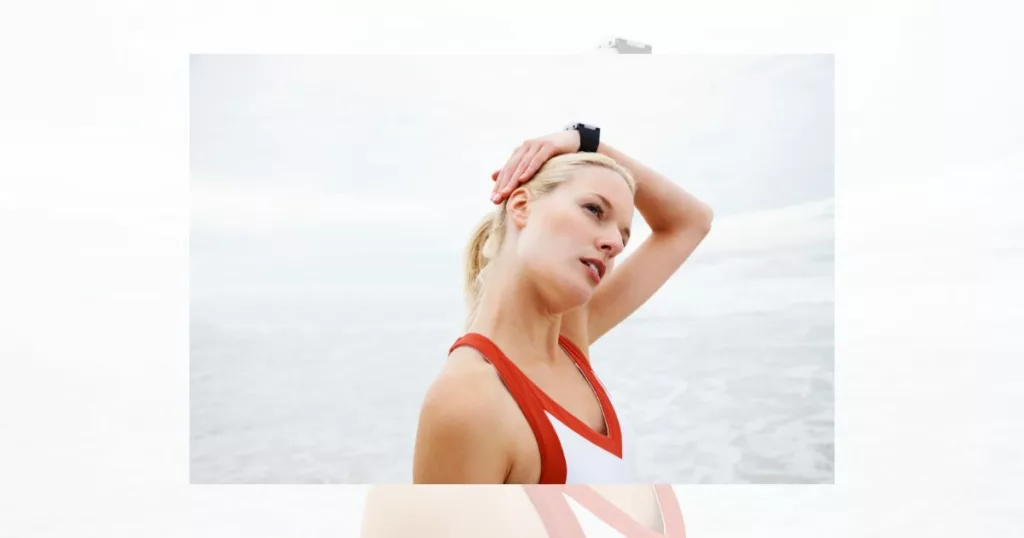 young woman doing a tilted neck stretch at the beach