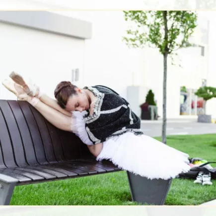 Ballet dancer stretching on a bench in the street